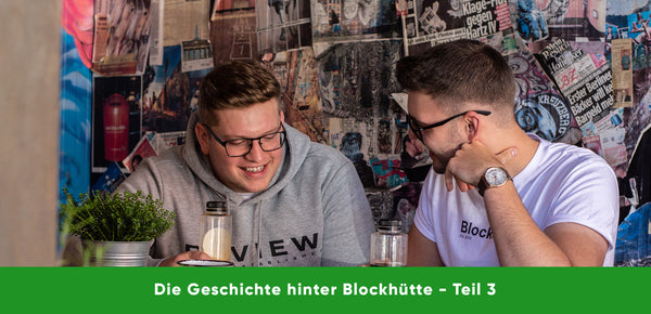 Malte und Nils, die Gründer von Blockhütte gemeinsam lachend an einem Tisch